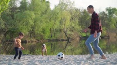 Baba, Oğul 'la Kum' da Futbol oynuyor. Genç adam ve küçük çocuk dışarıda, Nehir kenarında siyah ve beyaz futbol topuyla oynuyorlar.