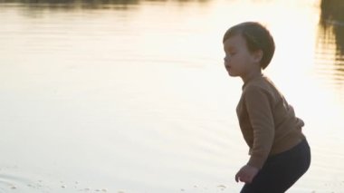  Nehir kıyısında duran ve suya taş atan küçük bebek. Yavaş Hareket