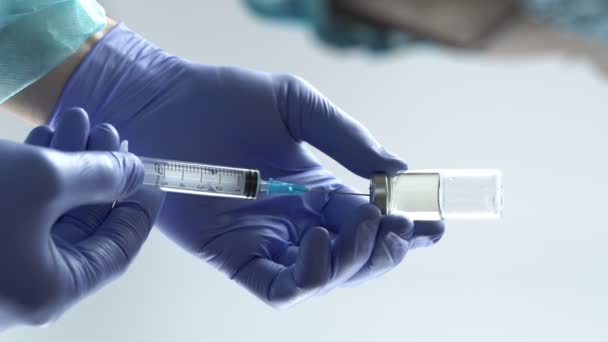 医療用手袋を着用している医師は ガラス瓶からのワクチンで注射器を充填します 縦のビデオ — ストック動画