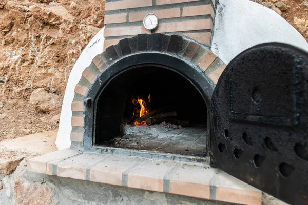Artisan wood oven built on the outside with the door open and fire inside