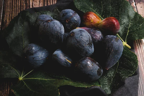 Figs in fig leaves on wooden table