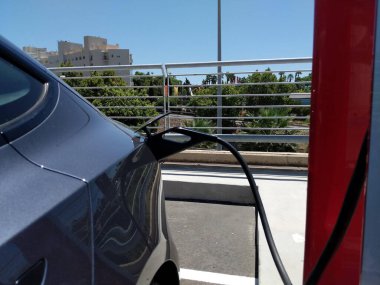 Electric car connected to charge the battery, outdoors
