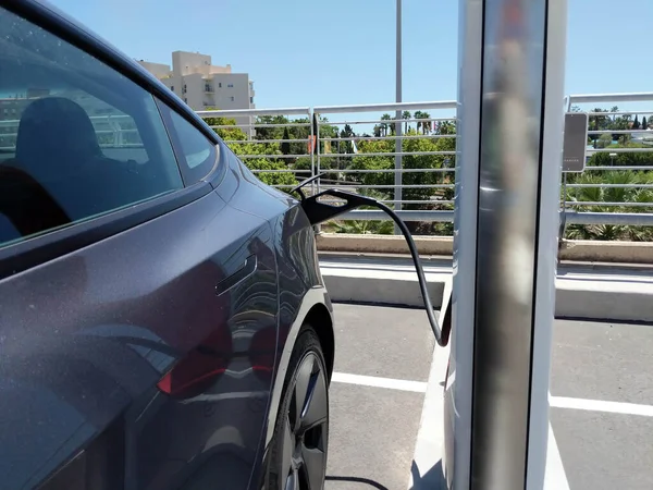Electric car connected to charge the battery, outdoors