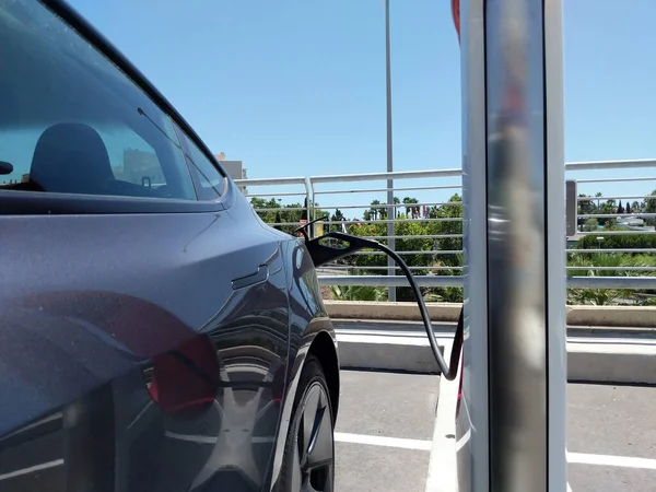 Electric car connected to charge the battery, outdoors