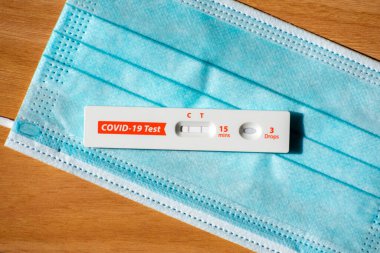 Mavi cerrahi maske üzerinde COVID-19 için hızlı test cihazı kullanarak pozitif test sonucu