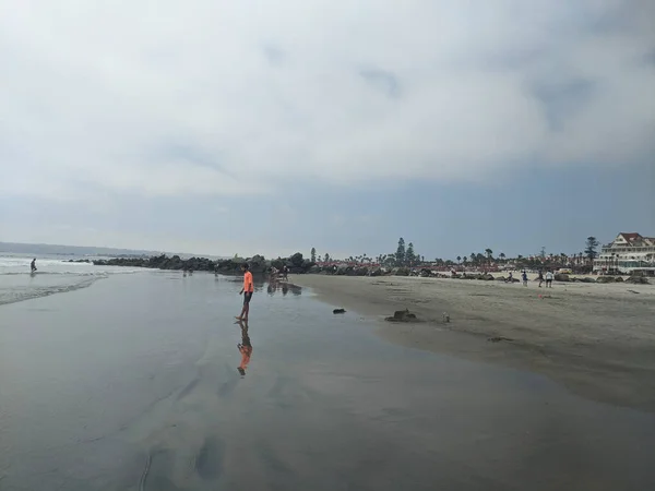 Odbicie Wodzie Mężczyzny Pomarańczowej Koszulce Stojąc Nad Brzegiem Oceanu Spokojnego — Zdjęcie stockowe