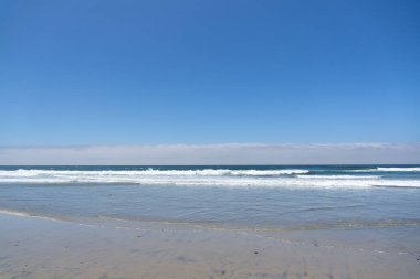 Yumuşak dalgalı kumsal. Temiz kumsalda beyaz köpük.