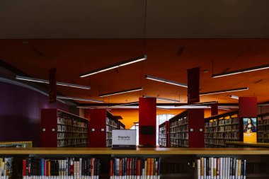 Boston, ABD - 22 Ekim 2021: Kütüphanedeki kitap dolu kitaplıklar. Dikdörtgen lambalar asılıyor.