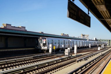 F metrosu Brooklyn, New York 'taki yüksek istasyona yaklaşıyor. Açık platformda tren rayları