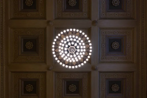 Tavana güzel bir avize ve oymalı bir tavanla bakıyorum.