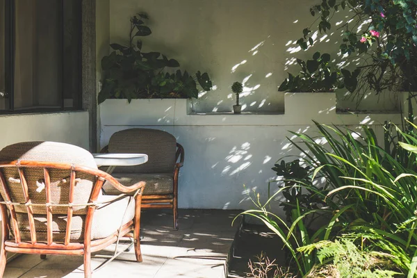在阳光灿烂的日子里 维兰达坐在木制椅子上 有植物的阴凉庭院 — 图库照片
