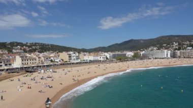 Costa Brava, Spain - April 19, 2022: Bird view of Tossa de Mar. Beach with resting tourists. Buildings along sandy beach on a sunny day