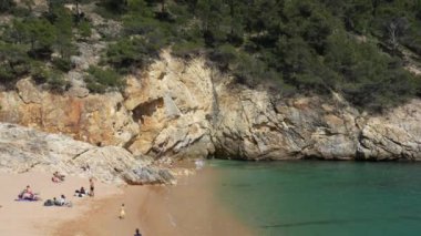Costa Brava, İspanya - 19 Nisan 2022: Costa Brava 'da Tossa de Mar' da engebeli bir kayalık kıyıdan Akdeniz manzarası. İnsanlar sahilde dinleniyor ve kaya tırmanışı yapıyorlar.