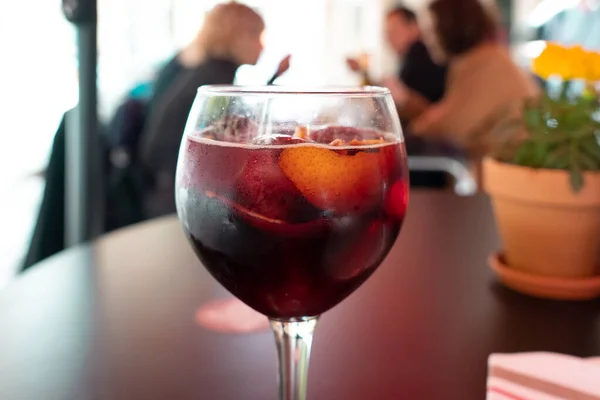 tasty red sangria with pieces of oranges in the wine glass. Blurry background in a bar