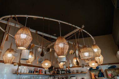 Bir kafede tavandan sarkan hasır lambalar. Dekoratif unsurları olan bir restoranda sayaç