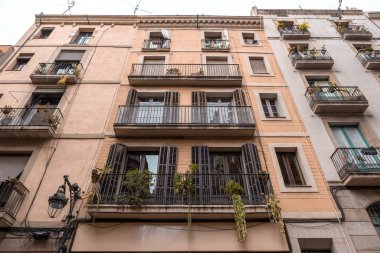 Exterior of apartment building with balconies and plants on the rails. Facade of the spanish building