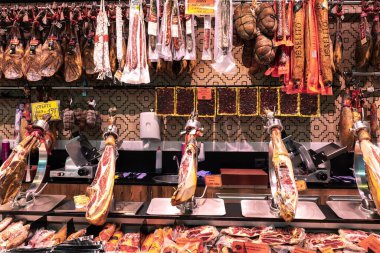 Barcelona, Spain - April 19 2022: Parts of meat displayed in the Sant Antoni market in Barcelona. Hanging pieces of ham