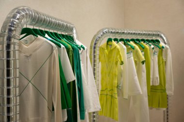 Shallow depth of field. Green shades of fashionable clothes hanging on the racks in a boutique store