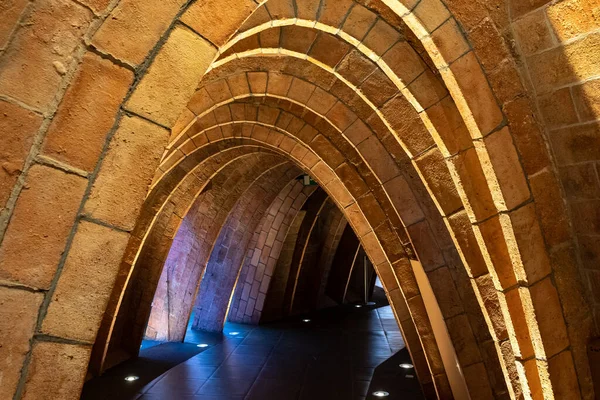 Arched tunnel built with brick walls and illuminated with floor lamps