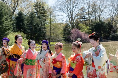 Brooklyn, New York - 30 Nisan 2022: Kimono giyen, geleneksel Japon kıyafetleri giyen ve parkta poz veren kadın ve kızlar