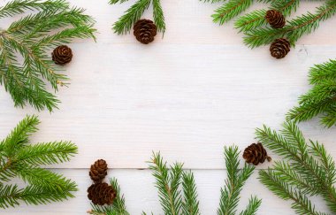 Beyaz ahşap arka planda ladin dalları ve koniler. Metnin için boşluklu Noel düzeni. 