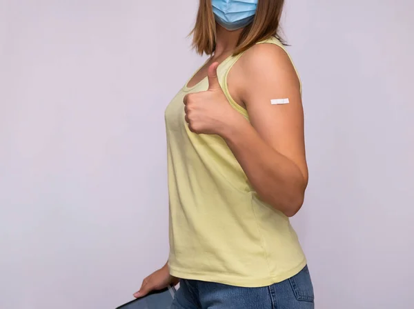 En flicka med ett plåster på axeln efter vaccination visar tecken på godkännande. — Stockfoto