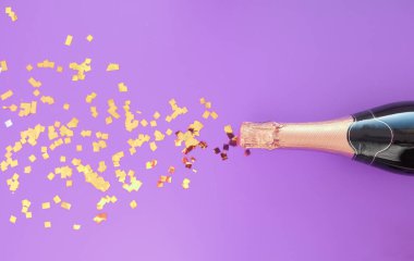 Bir şişe şampanya, üzerinde konfeti ve mor bir arka plan..