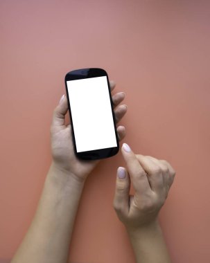 Kadının elleri telefonu tutsun. Fotokopi alanı olan pembe arkaplan üzerindeki minimalist düzen.