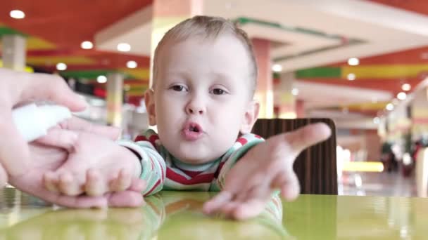 Mutter behandelt ihre Kinder vor dem Essen in einem Café mit einem Antiseptikum — Stockvideo