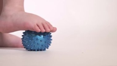 Bir çocuk ayağıyla ortopedik topu yuvarlıyor. Ayak egzersizi.. 