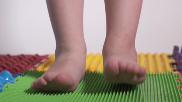 Il bambino fa esercizi sul tappeto ortopedico, gambe primo piano. — Video Stock