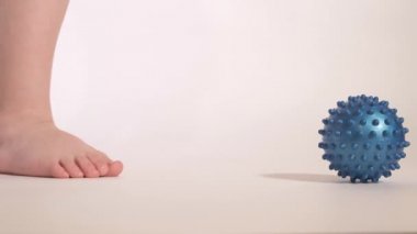 Bir çocuk ayağıyla ortopedik topu yuvarlıyor. Ayak egzersizi.. 