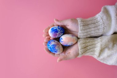 Kadınların elleri, boyanmış Paskalya yumurtalarını tutuyor. Kopya alanı olan bir düzen.