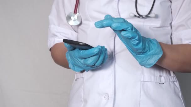 Tıbbi eldivenli bir doktor telefonuna bir mesaj yazmış. Telefona yakın çekim yapan eller