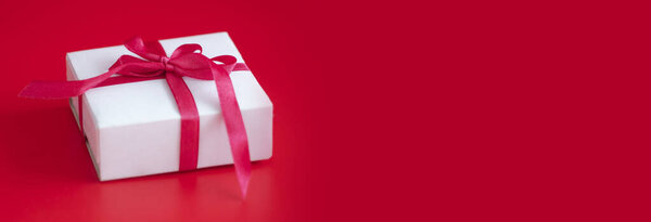 gift box with red ribbon on a red background, banner with space for text. High quality photo