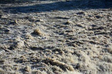 Swirling, churning waters of an earth-rich river that brings floods.