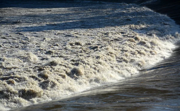 Swirling, churning waters of an earth-rich river that brings floods.