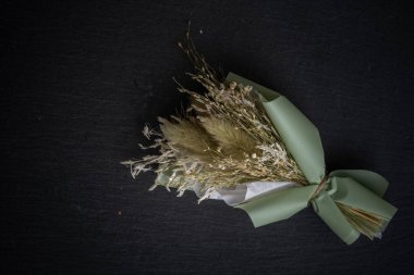 Siyah arka planda yeşil renklerde küçük bir buket kurumuş çiçek, inanılmaz bir sanat.