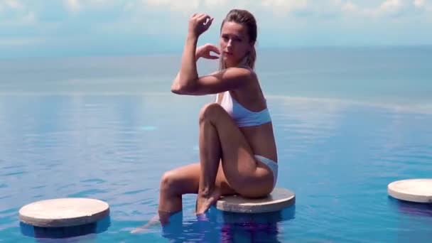 Seksowna dziewczyna. piękna kobieta. bielizna bikini dama model siedzieć krawędzi wody basenu na dachu luksusowy resort hotel morze ładne dekoracje długie ujęcie — Wideo stockowe