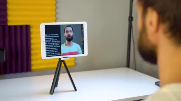 A young man records a video using a teleprompter on a tablet — ストック動画