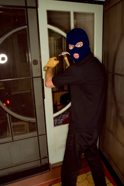 Um ladrão assaltando uma casa usando uma balaclava . — Fotografia de Stock