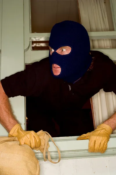 A burglar robbing a house wearing a balaclava.