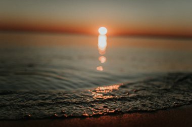 Gün batımında güneş ışınları dalgaya yansıyor.