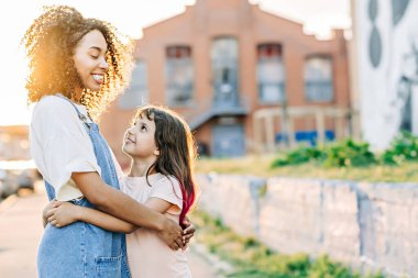 Mutlu çocuk ve bebek bakıcısı dışarıda güneşin altında gülümsüyor ve sarılıyor. Bebek bakıcılığı konsepti. Karışık ırk insanları
