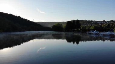 Sis yüzünden güneş doğarken insansız hava aracı nehrin üzerinde alçaktan uçuyor. Videolar 4K.