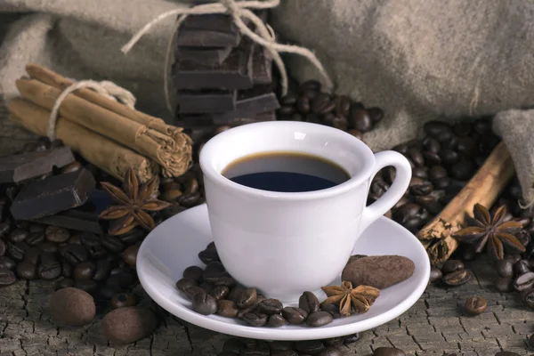 Kopp kaffe med kaffebönor, choklad och kryddor — Stockfoto