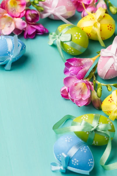 Huevos de Pascua de colores y flores en una mesa turquesa —  Fotos de Stock