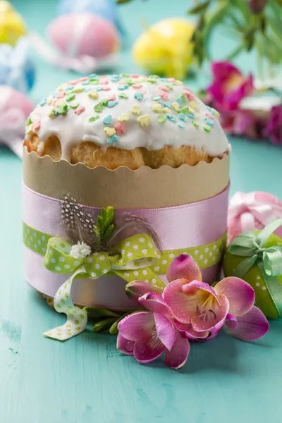 Pastel de Pascua, flores y huevos en una mesa turquesa — Foto de Stock