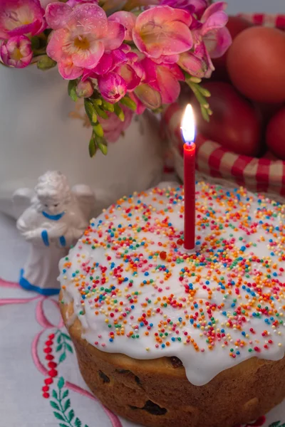 Velikonoční dort s rozsvícené svíčky, květiny, vejce a anděl figurka — Stock fotografie