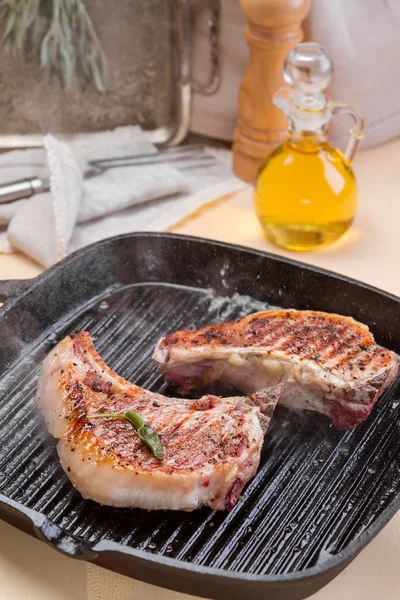 Steaming pork at grill frying pan on a kitchen table — Stock Photo, Image